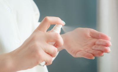 Девушка распыляет антисептик на руки